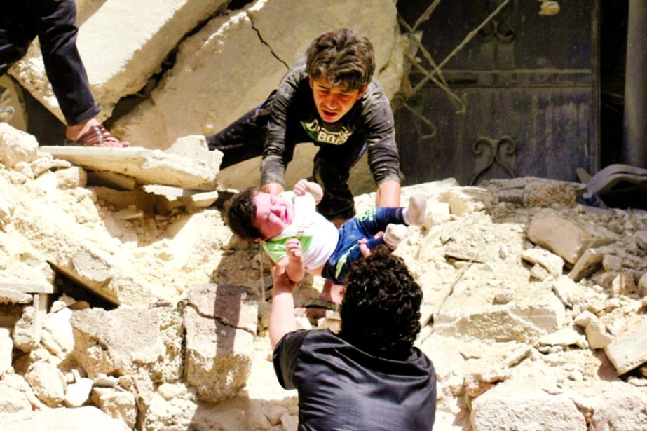 Syrians evacuate a toddler from a destroyed building following a reported air strike on the rebel-held neighbourhood of al-Kalasa in the northern Syrian city of Aleppo.