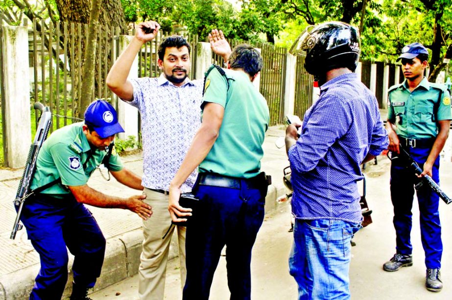 Law enforcers checking the commoners for security measures centering verdict against war criminal Motiur Rahman Nizami. The snap was taken from the High Court area on Tuesday.
