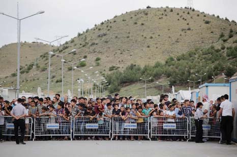 Refugees try to catch a glimpse of the German Chancellor visiting the refugee camp on the Turkish-Syrian border in Gaziantep.