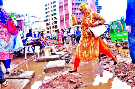 Photo shows a woman crossing the dilapidated road following digging by the service providers recently. This photo was taken from Motijheel Shapla Chattar area on Wednesday.