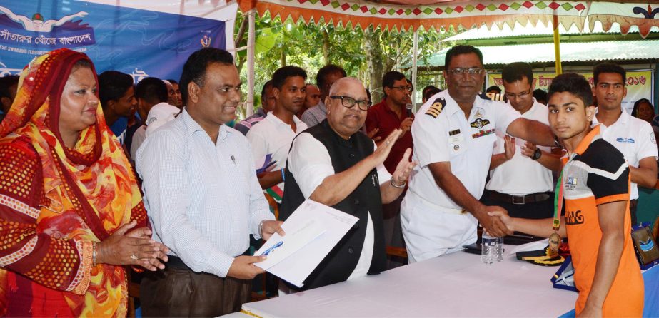 Deputy Commissioner of Tangail district Fazlul Rahman Khan distributes certificate to a winner swimmer of the 'Talent Hunt Swimmer Programme' at the District Lake in Tangail on Thursday. Bangladesh Swimming Federation and Bangladesh Navy jointly supervi