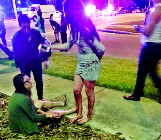 A woman sits on the ground outside the club while another party-goer, whose legs are covered in blood, stands beside her. Internet photo