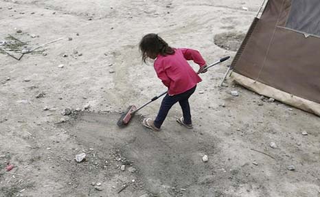 A girl uses a broom at a makeshift camp for refugees and migrants at the Greek-Macedonian border near the village of Idomeni, Greece.