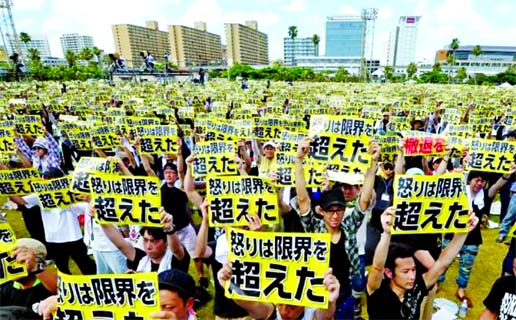 Protesters raise placards reading 'Anger was over the limit' during a rally against the U.S. military presence on the island and a series of crimes and other incidents involving U.S. soldiers and base workers, at a park in the prefectural capital Naha o