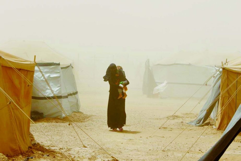 A woman, who fled from Falluja because of Islamic State violence, carries her child during a dust storm at a refugee camp in Ameriyat Falluja.
