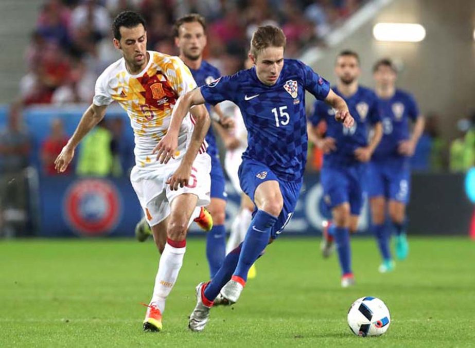 Croatia's Marko Rog (right) runs with the ball past Spain's Sergio Busquets during the Euro 2016 Group D soccer match between Croatia and Spain at the Nouveau Stade in Bordeaux, France on Tuesday