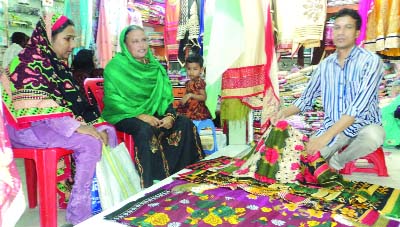 DUPCHANCHIA(Bogra): A shopkeeper talking to customers as EId shopping gaining momentum at Dupchanchia Upazila. This picture was taken from Faruk Cloth Store in Talukder Super Market in Upazila on Friday.