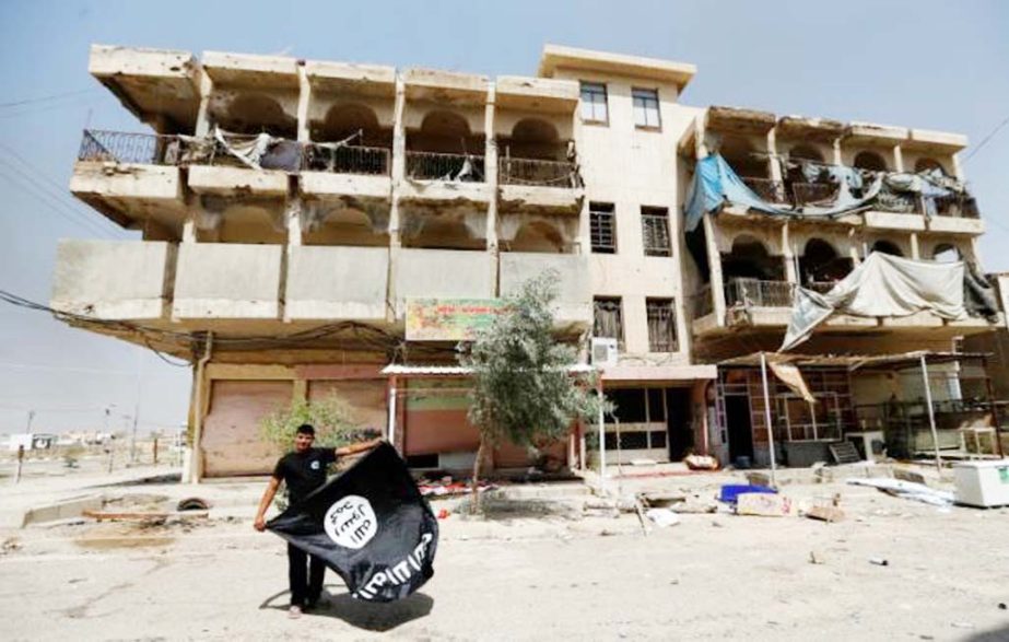 A member of the Iraqi security forces holds an Islamist State flag, after pulling it down from a building, in Falluja, Iraq, on Saturday.