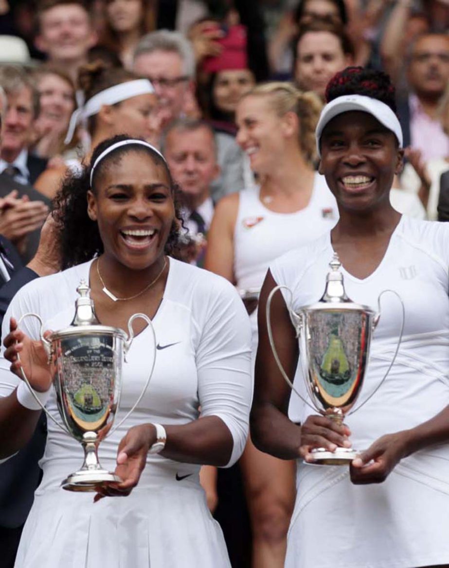 Serena Williams, left, and Venus Williams of the U.S hold their trophies after winning the women's doubles final against Yaroslava Shvedova of Kazahkstan and Timea Babos of Hungary on day thirteen of the Wimbledon Tennis Championships in London on Saturd