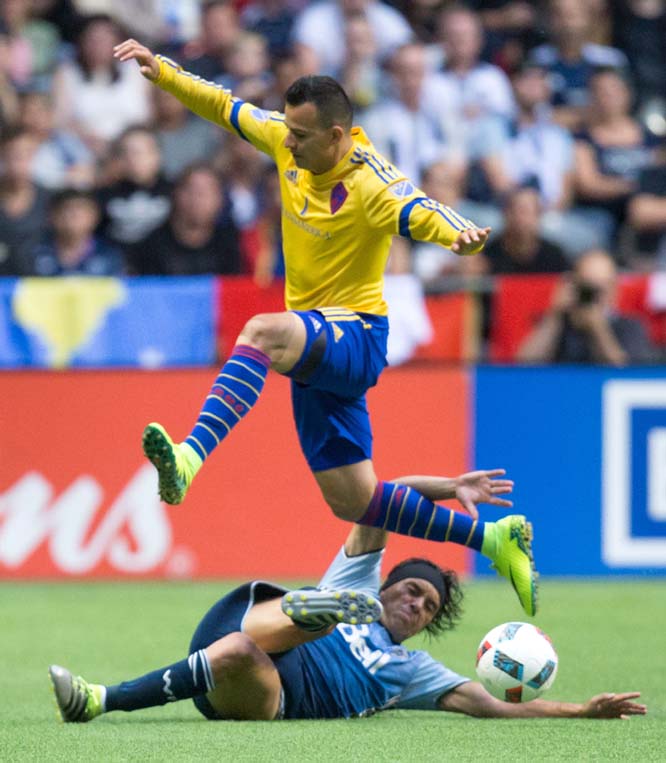 Colorado Rapids' Marco Pappa jumps over Vancouver Whitecaps' Christian Bolanos to avoid the challenge during the second half of an MLS soccer match on Saturday in Vancouver, British Columbia.