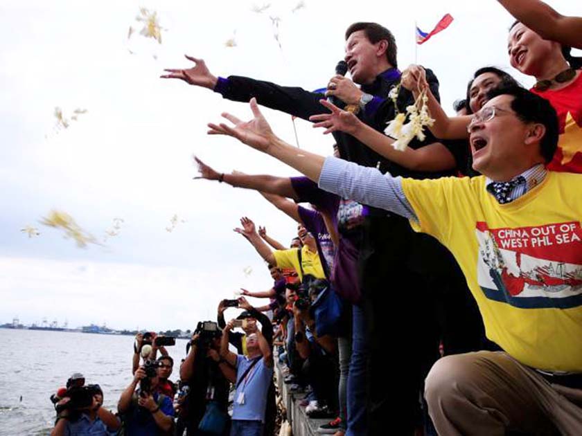 Protesters throw flowers while chanting anti-Chinese slogans during a rally by different activist groups over the South China Sea disputes, along a bay in metro Manila, Philippines on Tuesday.