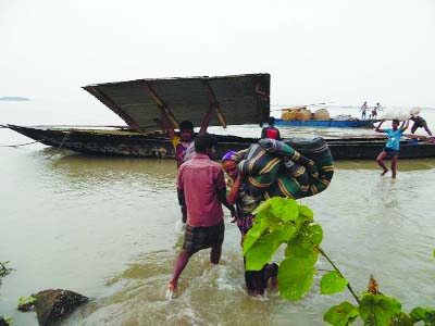 NILPHAMARI: Family members of flood affected Char Kharibari village are carrying their belongings to get shelter on the dam of Bangladesh Water Development Board (BWDB) at Dalia yesterday.