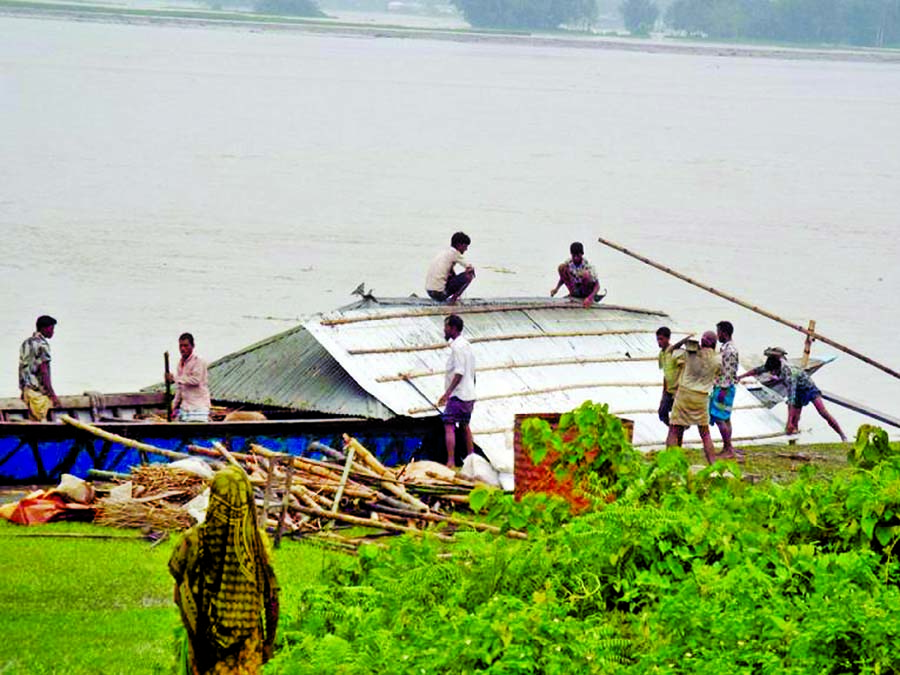 A flood affected family rush to the Flood Control Dam of Water Development Board by boat for taking shelter crossing the Teesta River. They also brought the remains of their houses including the dismantled tin-roof. This photo was taken on Monday.