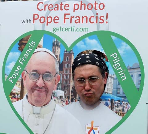 A piligrim poses with a picture installation of Pope Francis at the market square in Krakow, Poland on Monday.