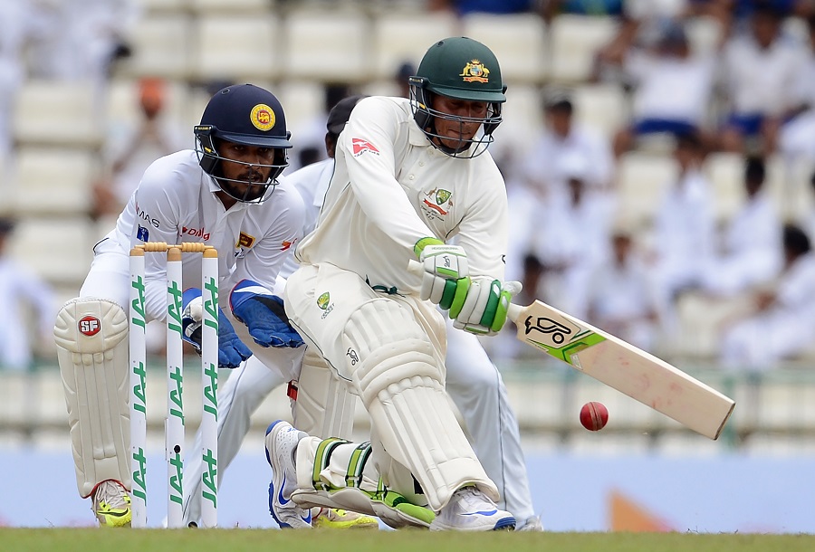 Australia's Usman Khawaja (R) plays a shot as Sri Lanka's wicketkeeper Dinesh Chandimal looks on during the first day of the opening Test cricket match between Sri Lanka and Australia at the Pallekele International Cricket Stadium in Pallekele on Tuesda