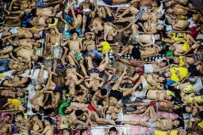 Inmates sleep on the ground of a basketball court inside the Quezon City jail at night in Manila