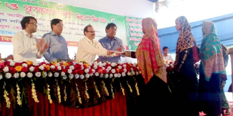 Divisional Commissioner of Chittagong Md. Ruhul Amin distributing profit share amount to the beneficiaries of the social a forestation programs under Ctg. North Forest Division in the inaugural session of the tree fair at Laldighi Maidan on Sunday.
