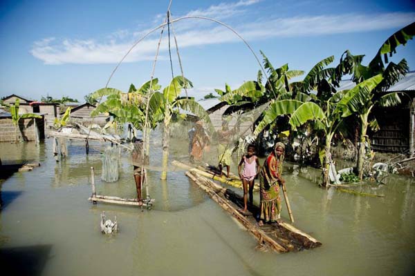 A flood affected family moves on a banana raft past a fishing net in Morigaon district, east of Gauhati, northeastern Assam state, India.
