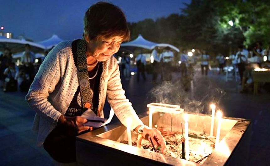 A woman lights up candle in front of cenotaph for the victims of the 1945 atomic bombing.