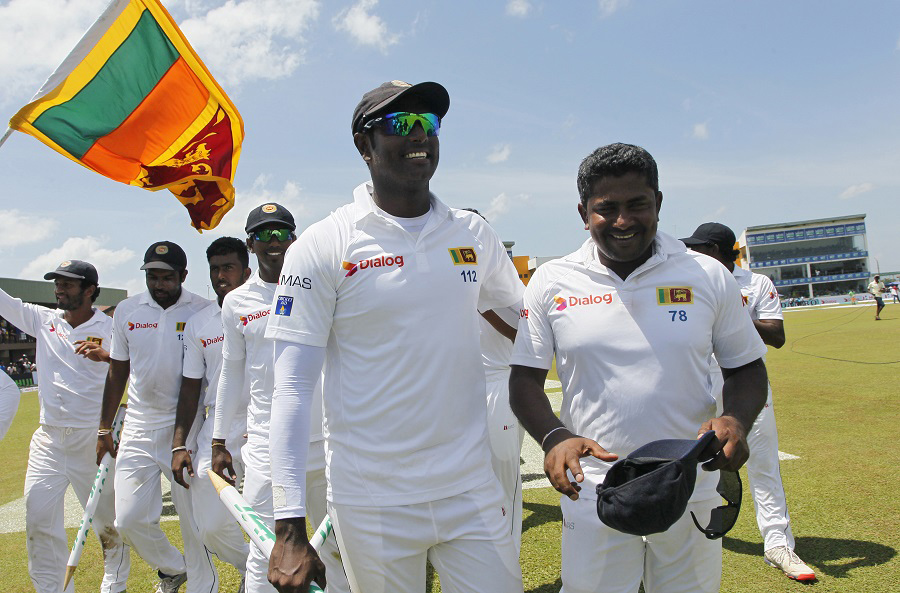 Sri Lankan cricketers Angelo Mathews (center) and Rangana Herath (right) with team members acknowledge the crowd as they celebrate their victory over Australia by 229 runs in the second Test cricket match in Galle, Sri Lanka on Saturday.