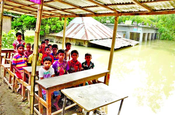 NEITHER BOOKS NOR KHATAS: They managed to turn up at their school inundated by flood. This photo was taken from Shariakandi of Bogra on Monday.