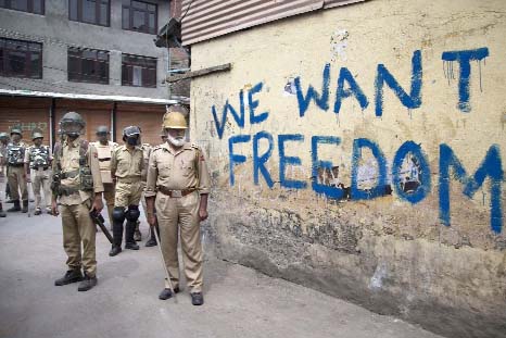 Indian policemen stand guard during a curfew in Srinagar, Indian-controlled Kashmir on Friday. Curfew and protests have continued across the valley amidst outrage over the killing of a top rebel leader by Indian troops .