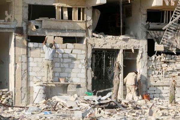 A man rebuilds a wall of a damaged building in the rebel held al-Katerji district in Aleppo, Syria.