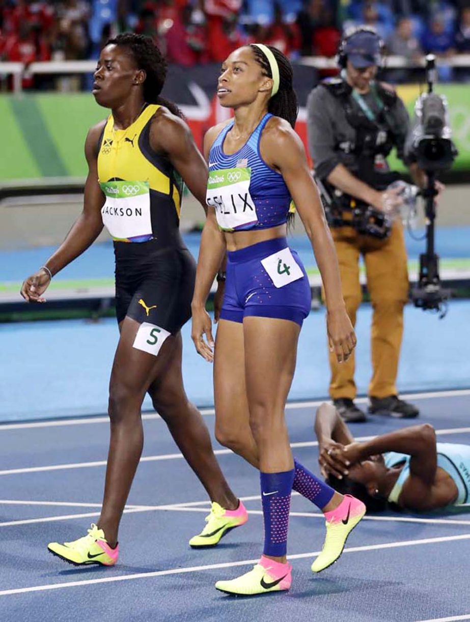 Bahamas' gold medal winner Shaunae Miller lies on the track as silver medal winner Allyson Felix (right) and Jamaica's bronze medal winner Shericka Jackson walk past during the athletics competitions of the 2016 Summer Olympics at the Olympic stadium in