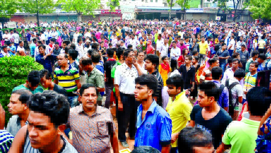 Panicked people including businessmen of Basundhara City Complex crowd the road in front of the complex after a devastating fire originated in the complex on Sunday.