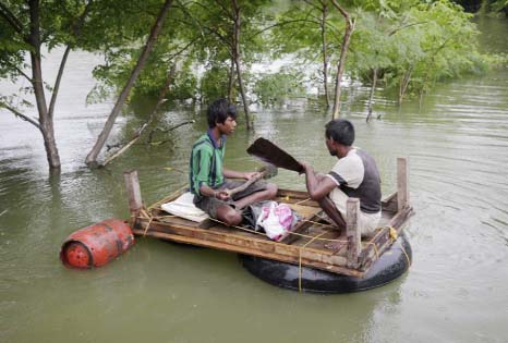Two men carry essentials like a gas cylinder to their temporary shelter by a makeshift raft after several areas were flooded in Allahabad, India on Monday.