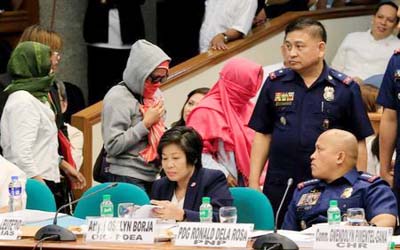 Philippine National Police (PNP) Director General Ronald Dela Rosa (seated R) looks at relatives of slain people during a Senate hearing investigating drug-related killings at the Senate headquarters in Pasay city, metro Manila on Monday.