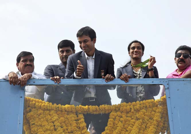 Pusarla Sindhu, second from right, one of the only two Indians to win medals at the just concluded Rio Olympics, displays her silver medal as she is brought home in a procession along with her coach Pullela Gopichand, third from left, upon their arrival a