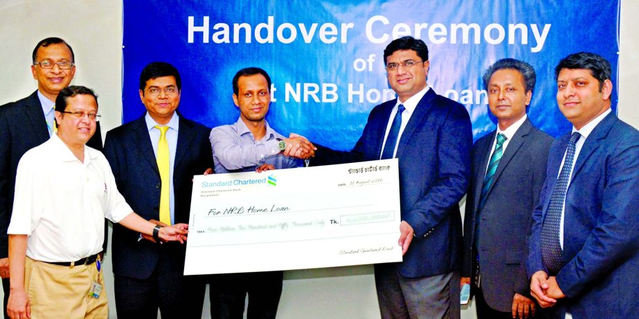 Aditya Mandloi, Head of Retail Banking, Standard Chartered Bank, Bangladesh, handing over a dummy cheque to Md Emran Hossain, a UK based Non Resident Bangladeshi, the very first recipient of NRB Home Loan at its head office on Saturday.