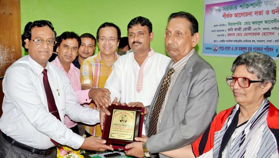 Justice Zainul Abedin hands over a crest to Principal of Government MM College, Jessore Pro Mohd. Mizanur Rahman for his outstanding contribution in education at a ceremony organized by Sher-e-Bangla AK Fazlul Haque Gobeshona Parishod at Central Library S