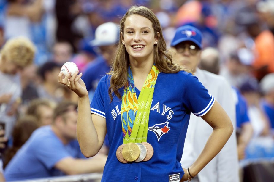 Swimmer Penny Oleksiak, who won four medals at the Rio Olympics for Canada, holds onto a major league baseball before throwing out the ceremonial first pitch before a baseball game between the Toronto Blue Jays and the Boston Red Sox in Toronto on Friday.