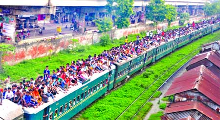 Thousands of home bound passengers overcrowding roof of train leaving Kamalapur Railway Station taking risk of life to celebrate Eid with their loved ones. This photo was taken from city's Khilgaon area on Sunday.