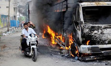 Men ride a motorcycle past a lorry in Bengaluru, which was set on fire by protesters after India's Supreme Court ordered Karnataka state to release 12,000 cubic feet of water per second every day from the Cauvery river to neighbouring Tamil Nadu, India