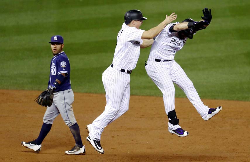 Colorado Rockies' Nick Hundley (center) celebrates with pinch-hitter Daniel Descalso after Descalso drove in the winning run, as San Diego Padres second baseman Alexi Amarista walks past at the end of a baseball game on Friday in Denver. Colorado won 8-7