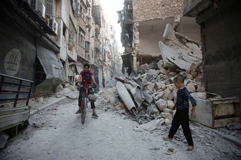 Syrians walk through rubble following an airstrike on the rebel-controlled neighbourdhood of Karm al-Jabal on Sunday.