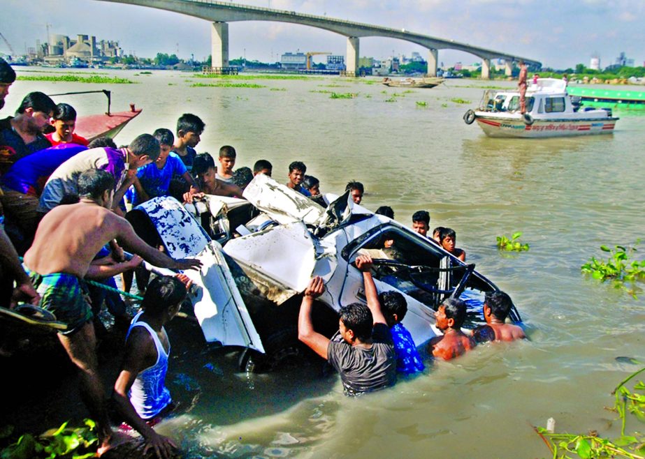 Firefighters trying to salvage an ill-fated car after it fell into the Dhaleswari river by breaking railing Muktarpur Bridge in Munshiganj on Saturday.