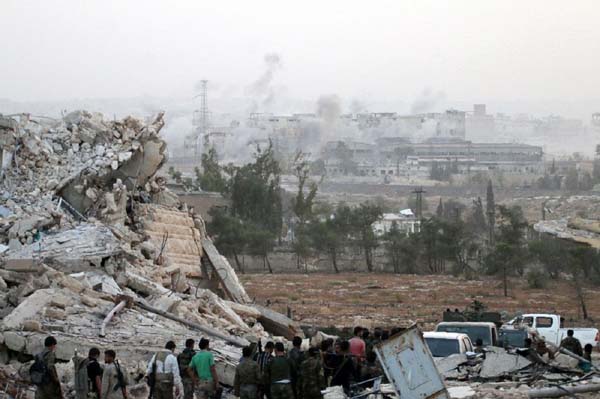 Syrian regime forces gather at the Kindi Hospital as smoke billows following airstrikes on Aleppo.