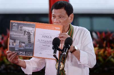 Philippine President Rodrigo Duterte holds up a certificate showing a Glock 30 handgun, awarded to him by a Philippine firearms importer for his fight against illegal drugs, in Manila