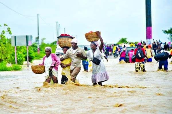 People try to cross the over flowing Rouyonne river, following Hurricane Matthew in the commune of Leogane. Internet photo