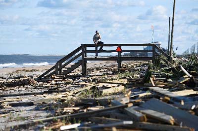 A stands on a damaged boardwalk at a debris covered beach in St Augustine, Florida, on Saturday, after Hurricane Matthew passed the area