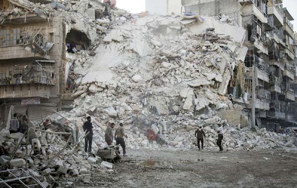 Members of the White Helmets search for victims amid the rubble of a destroyed building following reported air strikes in Aleppo on Monday.