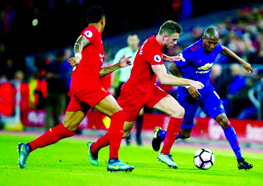 Liverpool's Jordan Henderson (centre) challenges for the ball with Manchester United's Ashley Young (right) during the English Premier League soccer match between Liverpool and Manchester United at Anfield stadium in Liverpool, England on Monday.