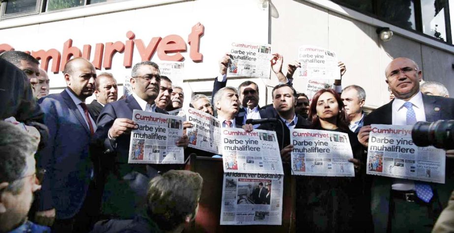 Journalists and lawmakers hold a latest copy of Cumhuriyet newspaper outside its Istanbul headquarters after police detained chief editor Murat Sabuncu and two columnists of Turkey's opposition Cumhuriyet newspaper and had warrants to detain 10 other sen