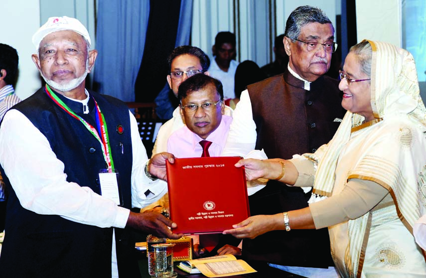 Prime Minister Sheikh Hasina handing over National Cooperatives Award to President of Feni Zila Muktijoddha Sangsad Unit Command Mir Abdul Hannan in Osmani Memorial auditorium in the city on Saturday in observance of 45th National Cooperatives Day-2016.