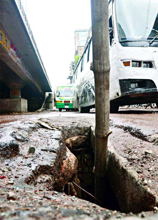 DEATH TRAP! A big pothole developed on the busy thoroughfare adjacent to the flyover at Malibagh point. A bamboo pole has been put up there to warn the people against any possible danger. This photo was taken on Sunday.