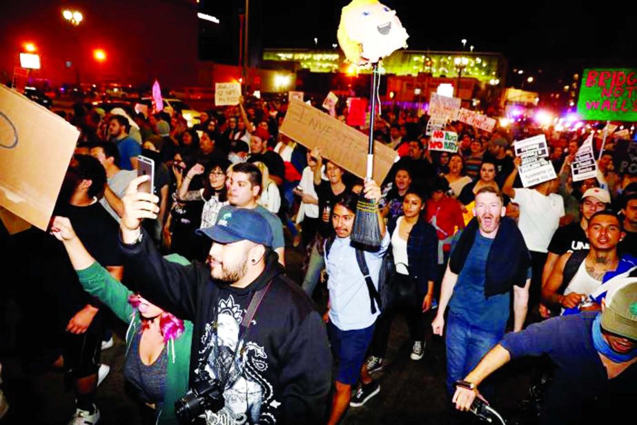 A demonstrator holds a pinata head of Donald Trump on a stick as they march in protest through the streets of downtown Los Angeles in protest following the election of Republican Donald Trump as President of the United States in Los Angeles, California No